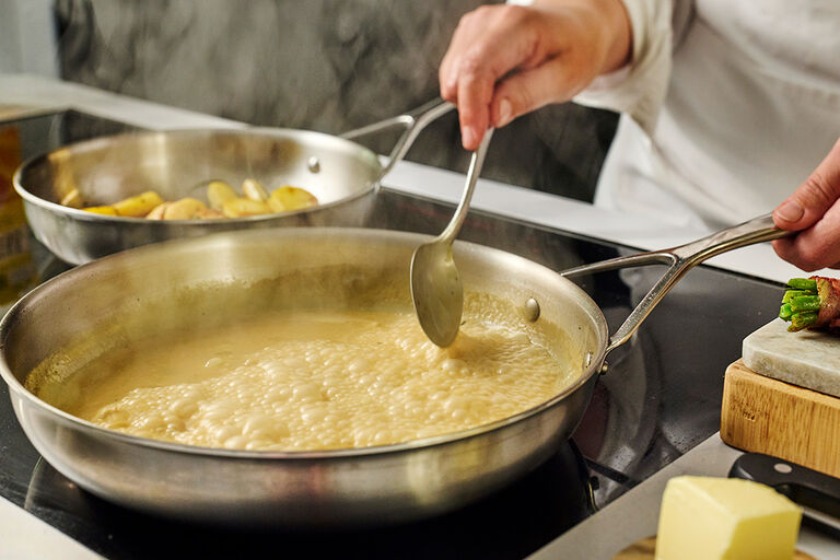 Bouillon toevoegen aan een pan om te deglaceren